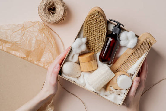 Box of natural beauty products including a brush, bottles, and cotton on a beige background